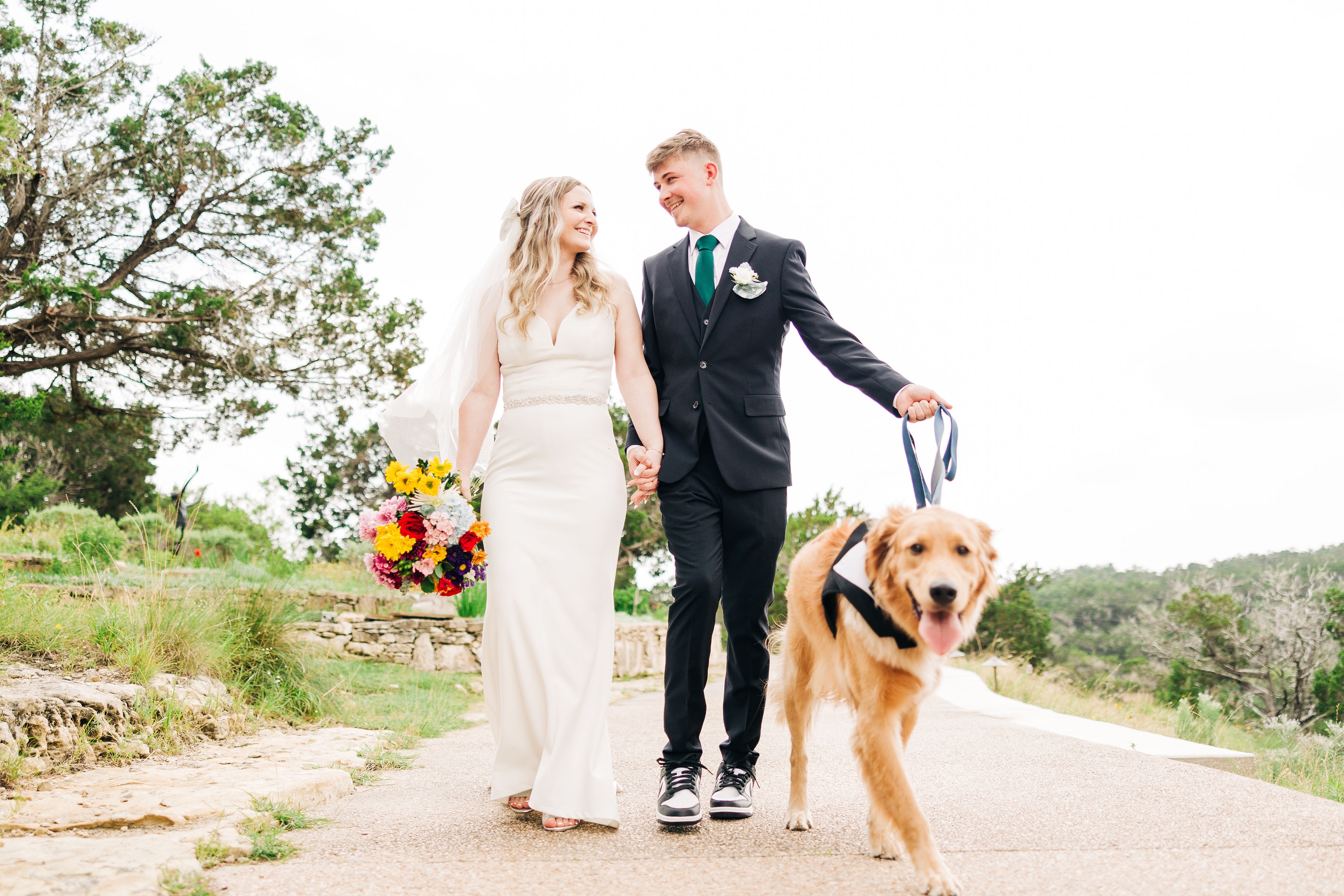 A couple walks down the path of Capel Dulcenia, led by their golden retriever in the warm glow of the sun.