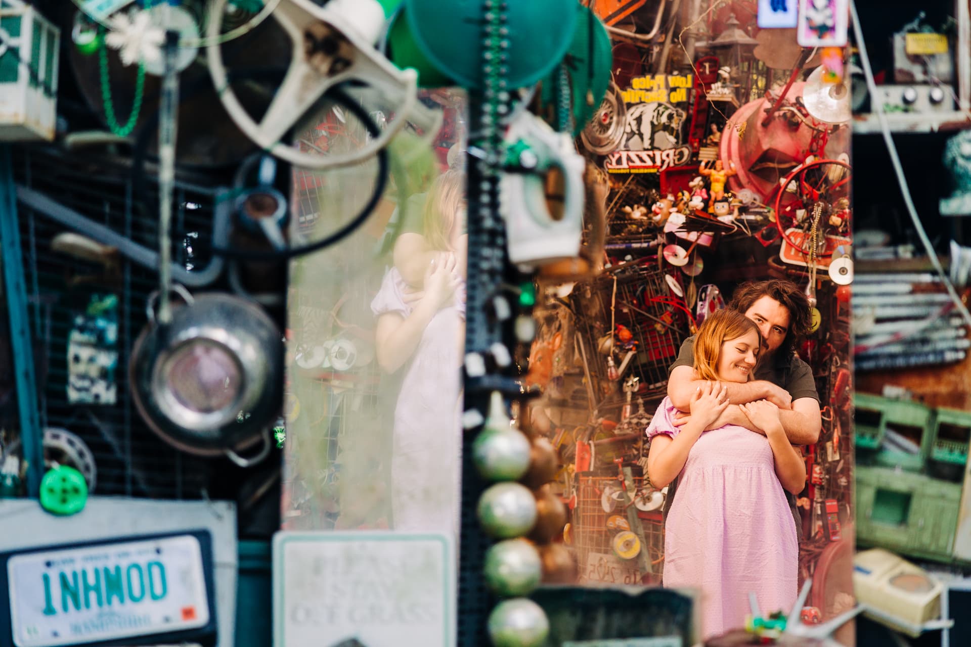 Couple laughing together surrounded by the colorful found-object sculptures and vintage signs inside the Cathedral of Junk