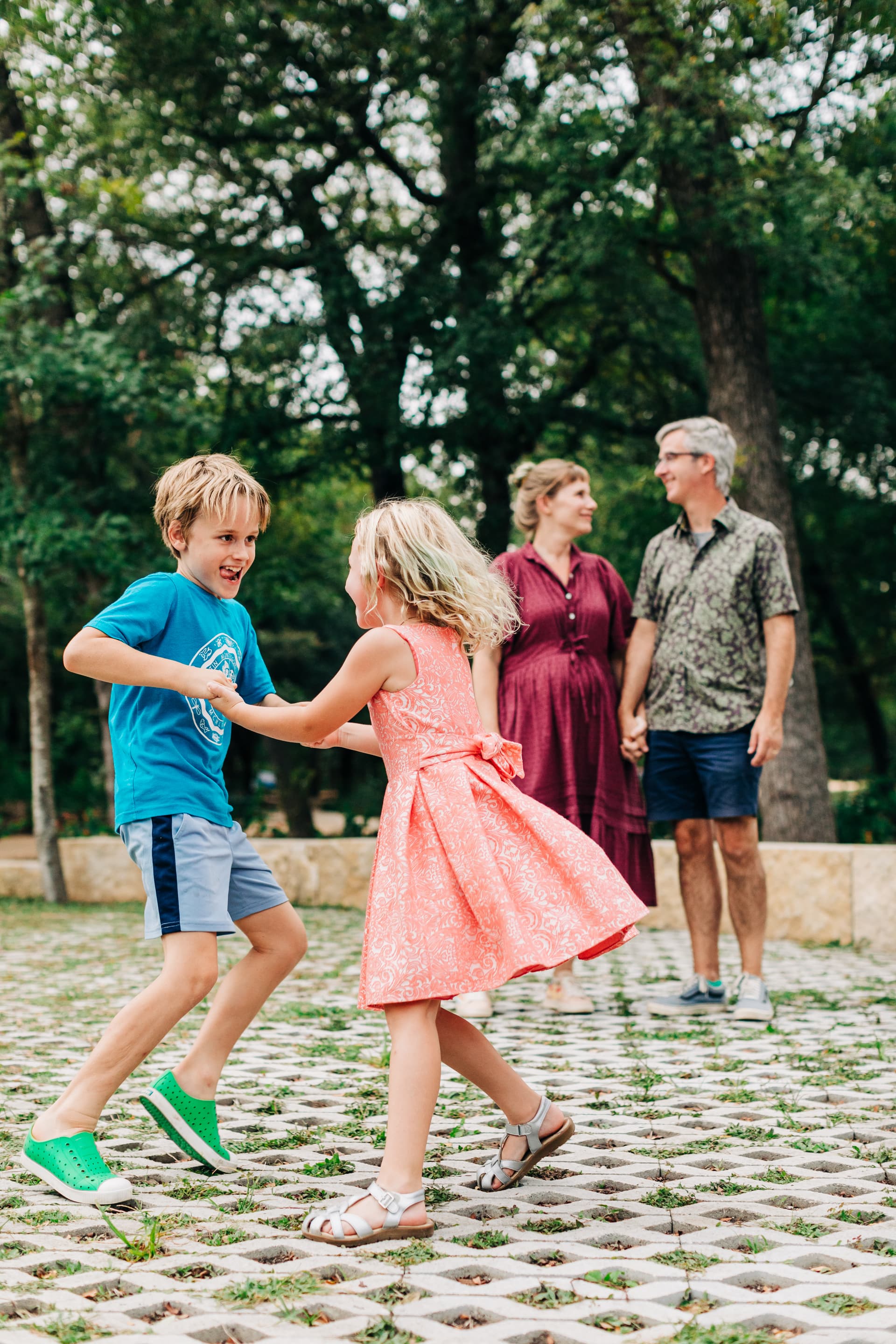 Candid family play moment — kids chasing bubbles, running through grass, or being tickled by a parent while everyone is laughing and completely forgetting about the camera