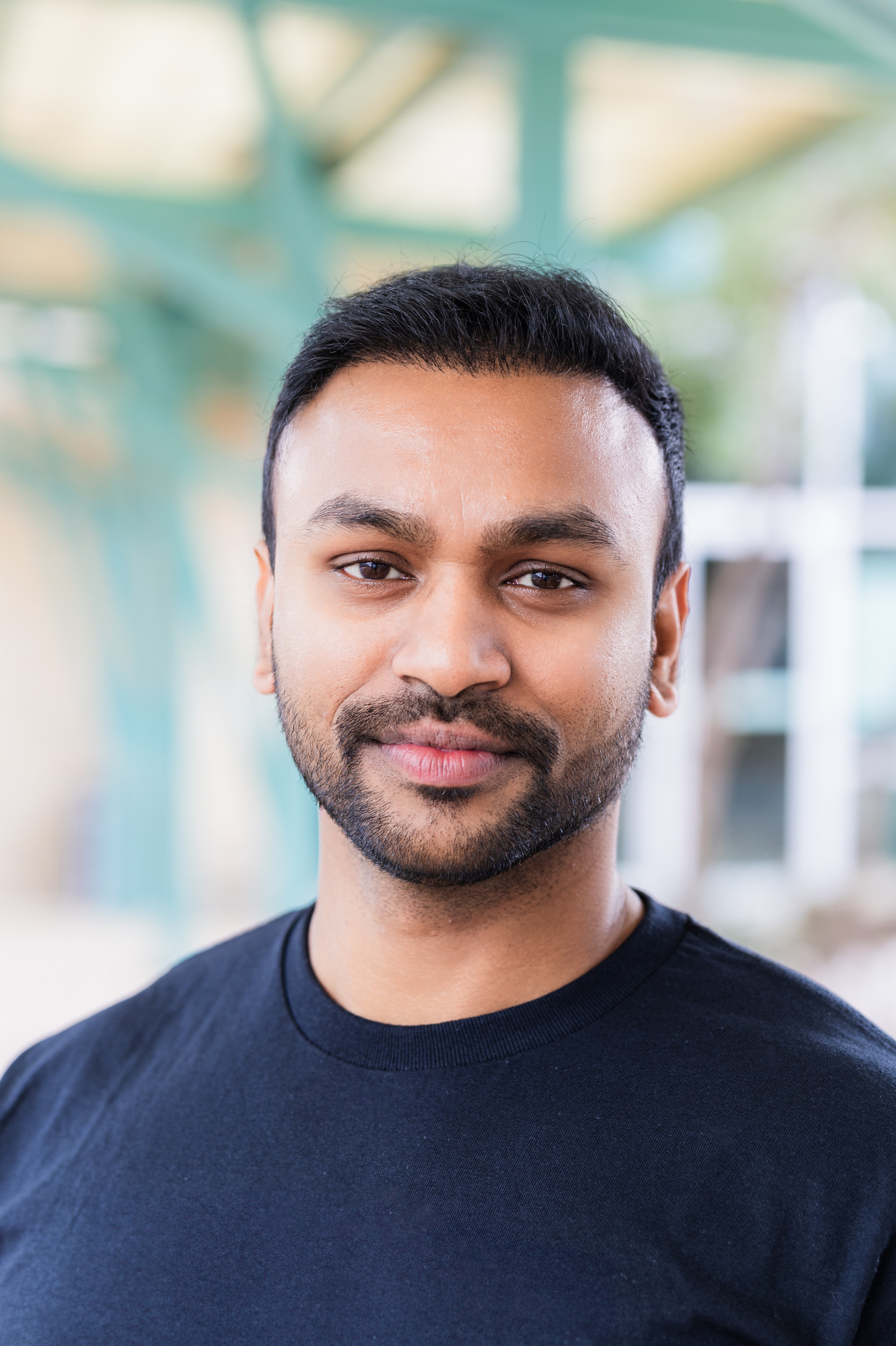 a headshot of a man taken in natural light, with a soft smile and dynamic background showing the client's office patio