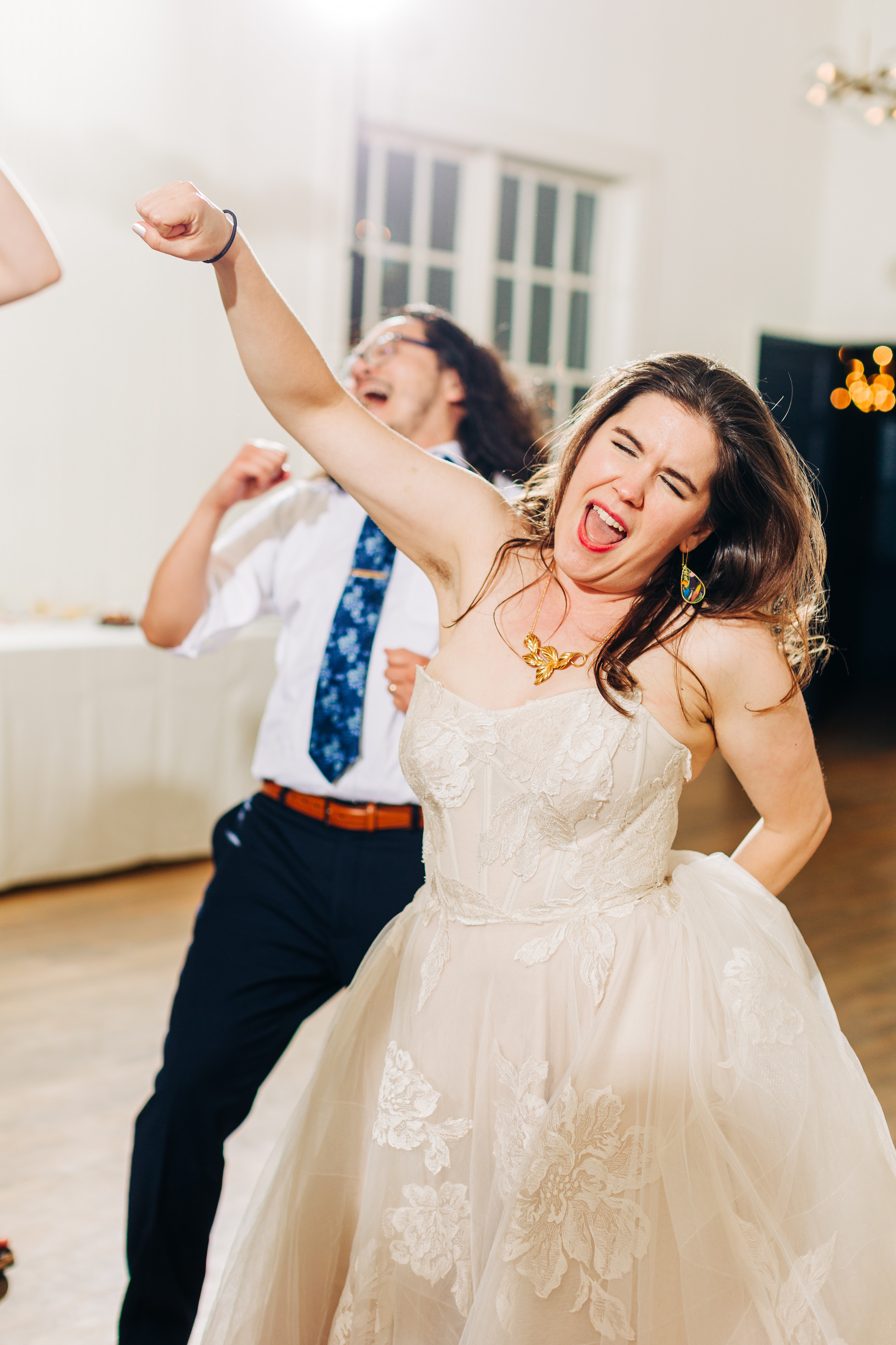 Candid dance floor moment at a wedding reception with guests laughing and celebrating, shoes off, full of genuine energy