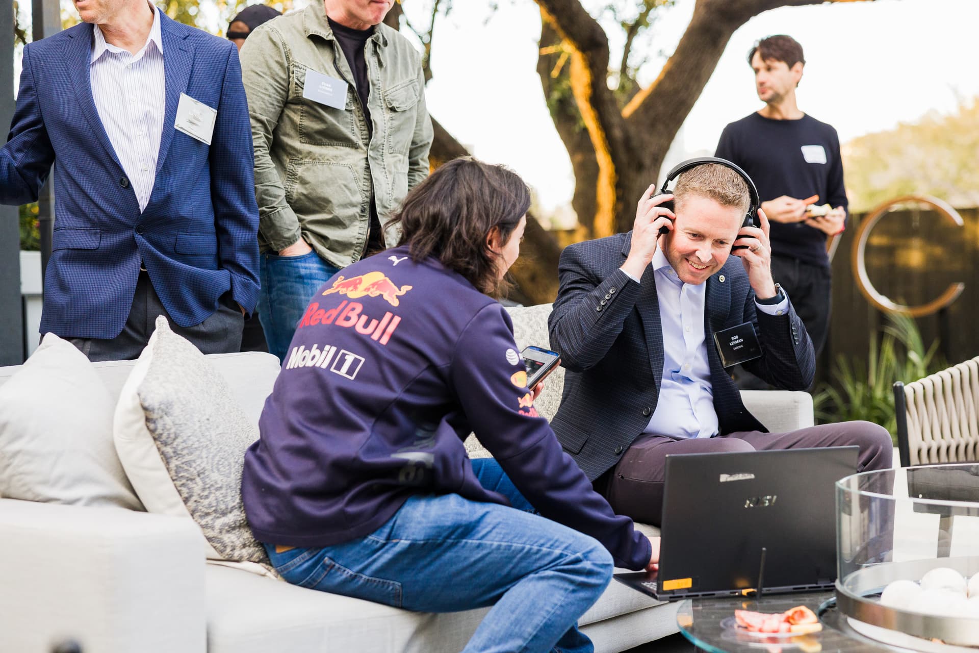 Candid moment of two SXSW attendees in animated conversation at a cocktail reception, warm ambient lighting showing off a new product launch.