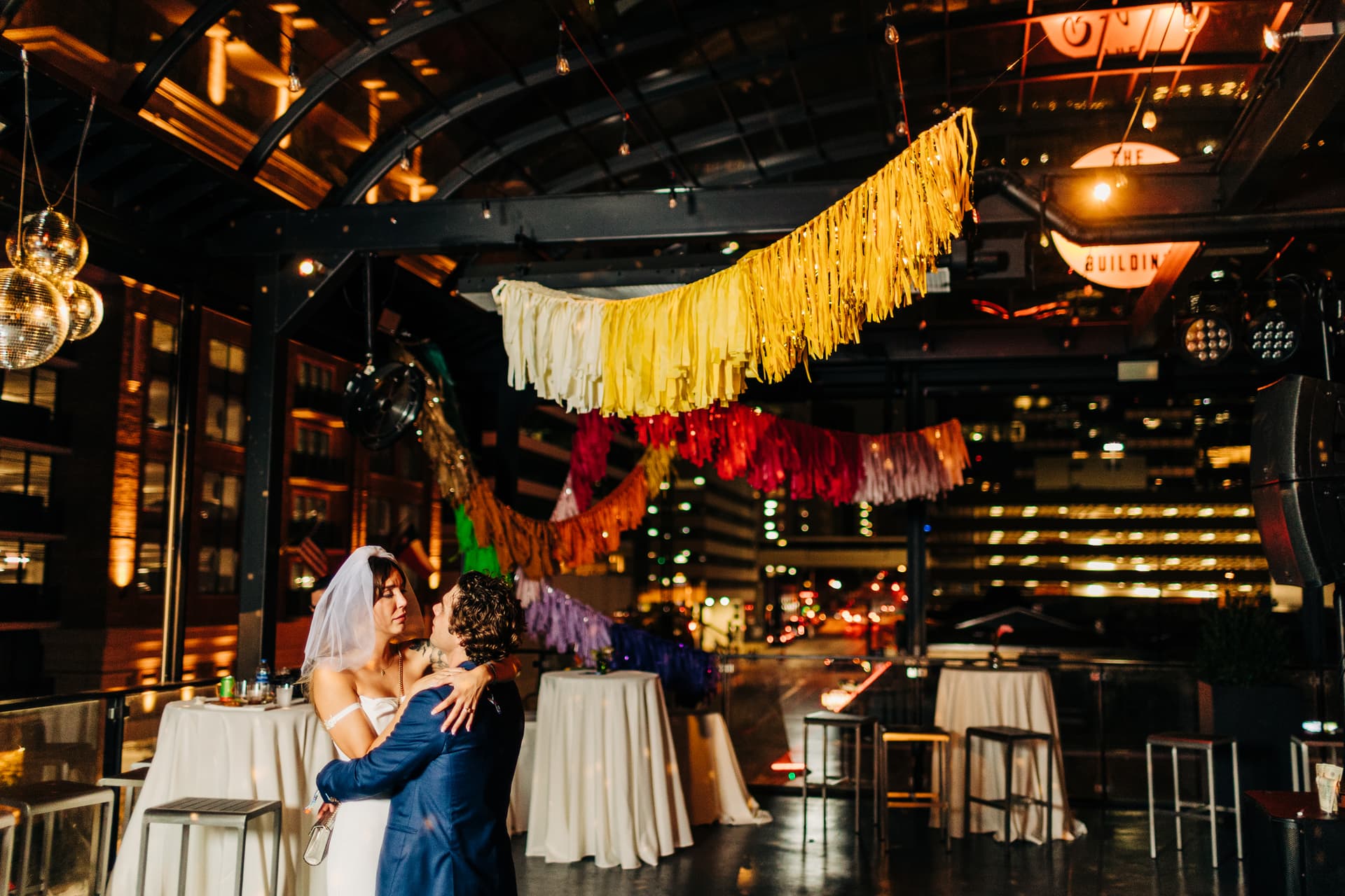 night time couples dancing portrait on the open-air top floor of The Riley Building with the downtown Austin skyline glowing in the background
